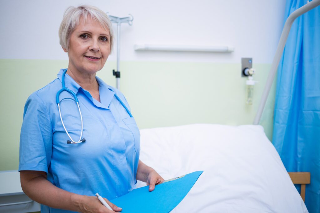 GP and person sitting on bed. GP with clipboard writing. Shot of body only.